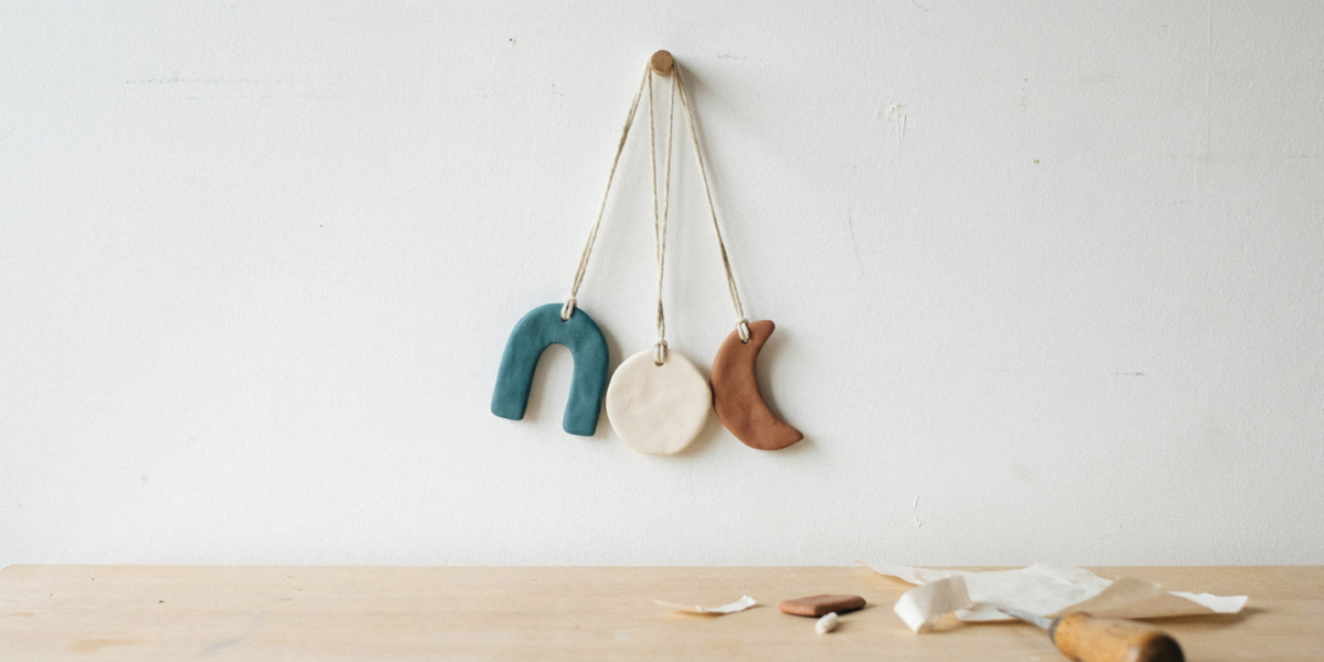 A wall hanging of painted clay shapes hung from a wooden dowel