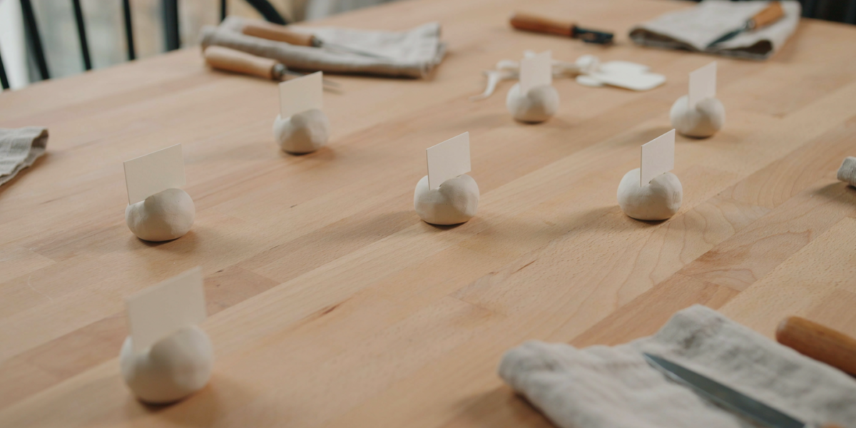 Small clay place card holders with paper name cards on a table