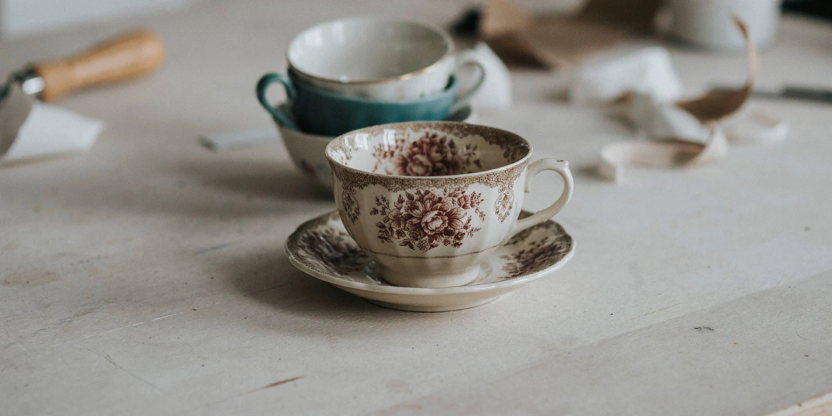 A soy candle in a thrifted floral teacup on its saucer