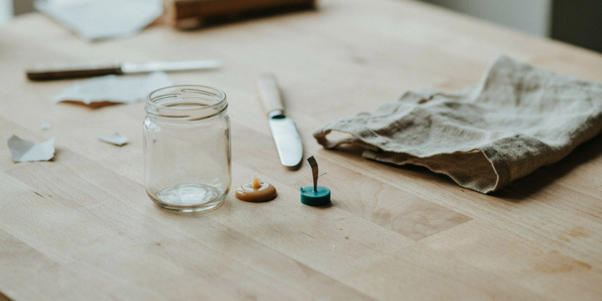 An empty candle jar being cleaned with the old wax disk beside it