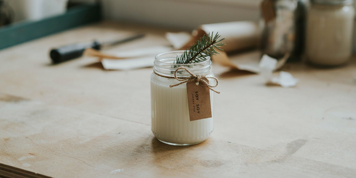 A soy candle in a ribbed thrifted glass jar with a kraft paper tag