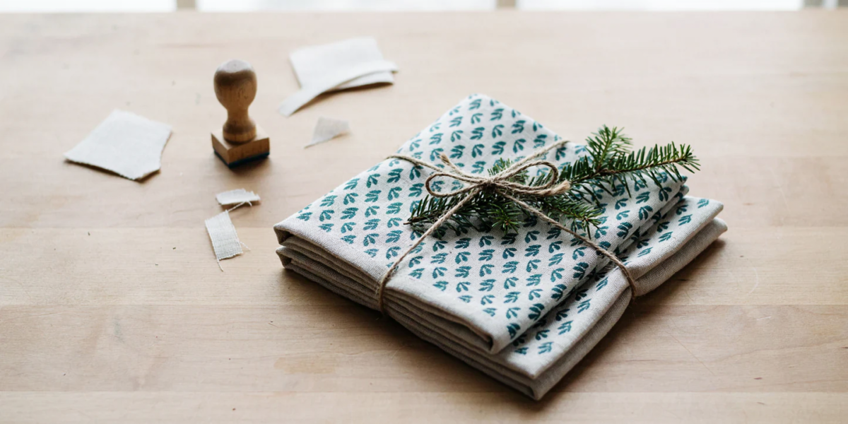 Two folded tea towels stamped with a small leaf pattern tied with twine
