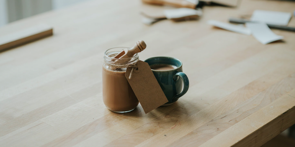 A jar of hot cocoa mix with a wooden spoon and a small tag