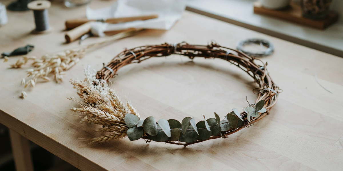 A grapevine wreath with a crescent of wheat and eucalyptus along the bottom