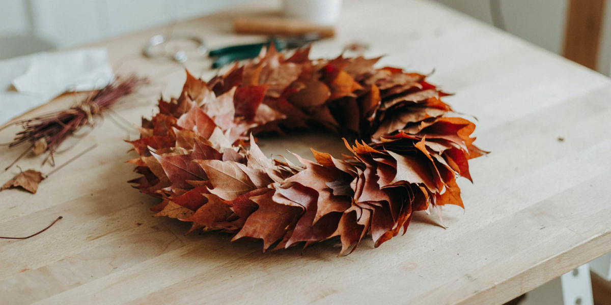A full wreath of overlapping faux maple leaves in rust and orange tones