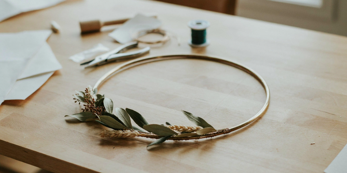 A brass hoop with a spray of autumn leaves and wheat wired to one side