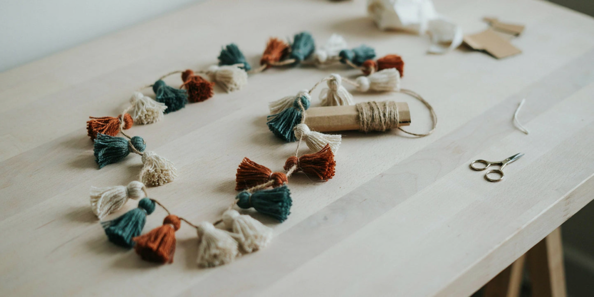 A garland of small yarn tassels in muted colors strung on twine