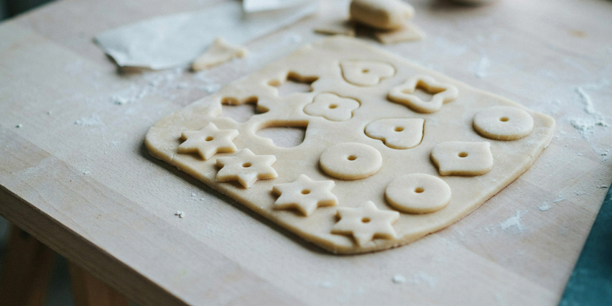 Pale salt dough ornaments on a baking sheet, cut in simple shapes