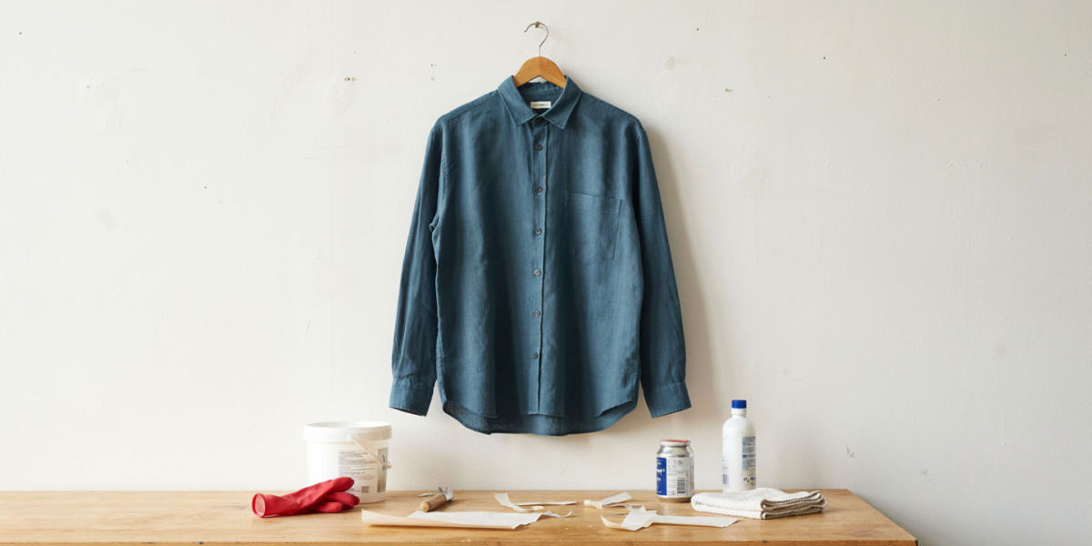 A white linen shirt dyed deep teal drying on a hanger