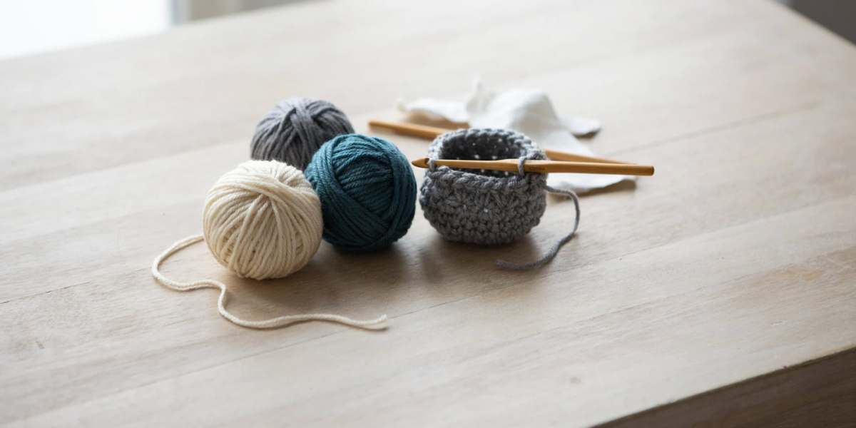 Balls of T-shirt yarn in different colors next to a small crocheted basket