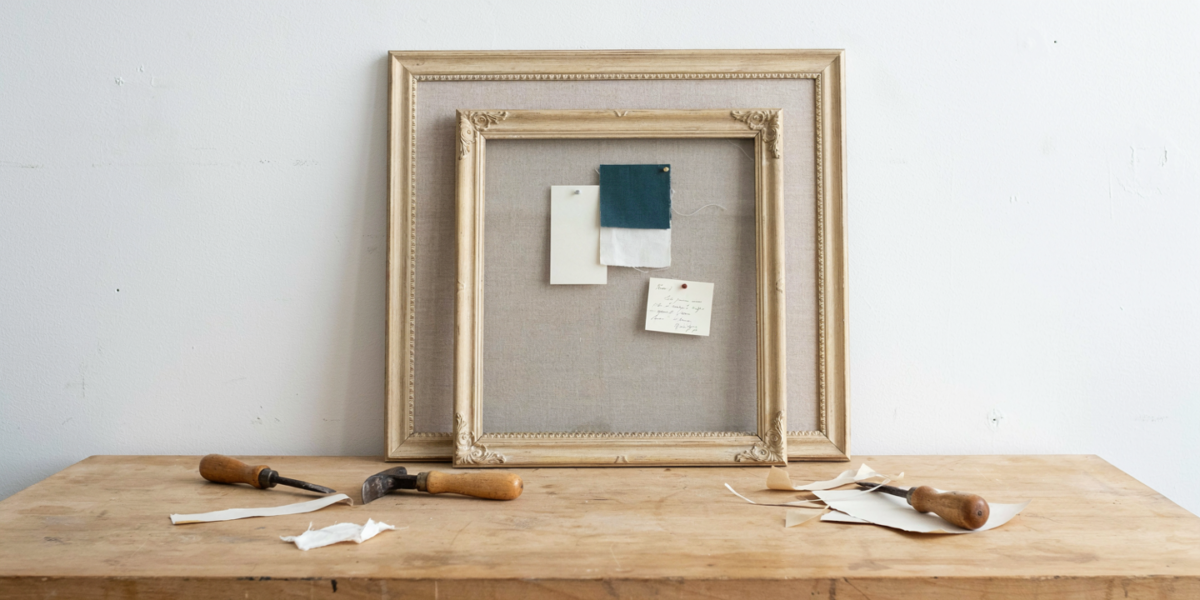 An ornate thrifted frame turned into a linen-covered pinboard