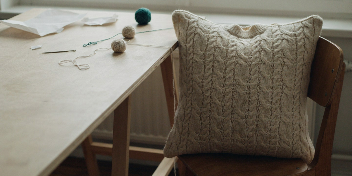 A chunky cream knit sweater turned into a pillow cover on a chair
